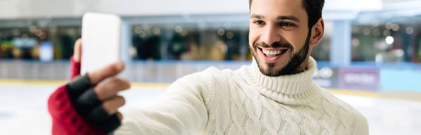 panoramic shot of happy man taking selfie on smartphone on skating rink - Fotó, kép
