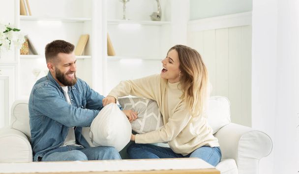 Young couple having pillow fight, playing and having fun - Photo, image
