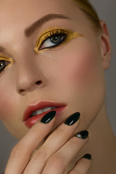 Half Beautiful close up sexy young woman evening make up dark eye eyelashes dyed and gold liner, makeup artist cosmetic beauty salon spa. Long green nails, clean skin and natural nude lips. - 写真・画像