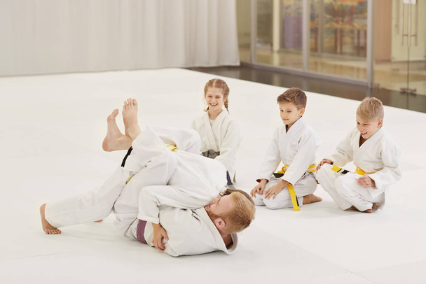 Trenér bojuje a ukazuje techniku karate pro děti v tělocvičně - Fotografie, Obrázek