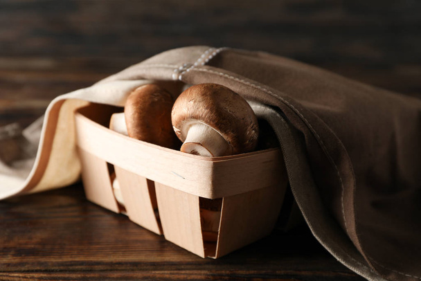 Champignons en handdoek in container op houten ondergrond, dicht u - Foto, afbeelding