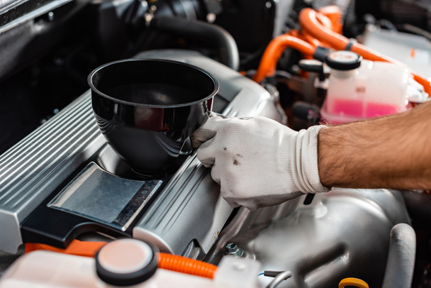 cropped view of mechanic holding oil funnel near car engine - Foto, Imagen