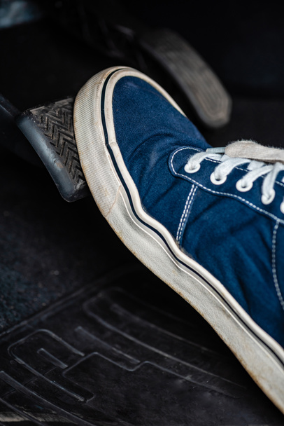 Spor ayakkabılı tamircinin arabanın fren pedalına basışının kısmi görüntüsü - Fotoğraf, Görsel