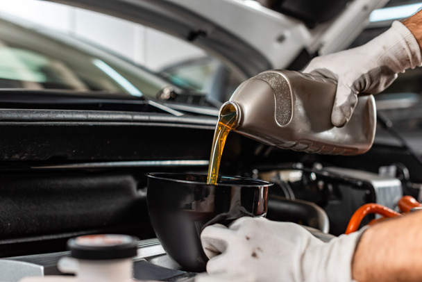 partial view of mechanic pouring motor oil at car engine - Photo, Image