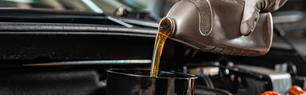 partial view of mechanic pouring machine oil at car engine, panoramic shot - Photo, Image