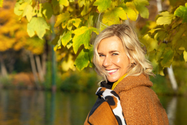 blond woman in her 40s outdoors enjoying the autumn sun - Fotoğraf, Görsel