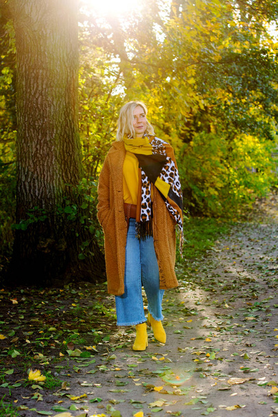blond woman walking in park and enjoying the autumn sun - Foto, afbeelding
