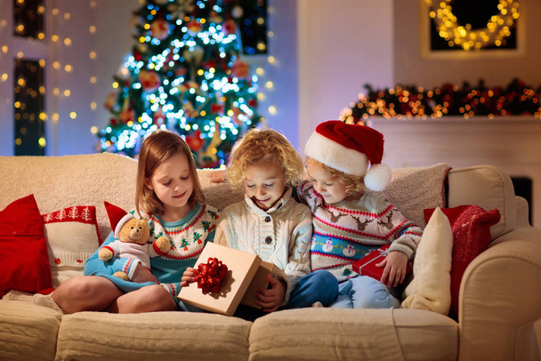 Niño en el árbol de Navidad. Niños en la chimenea en Navidad
 - Foto, imagen