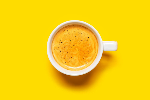 Black coffee in a cup on a yellow background - Фото, изображение