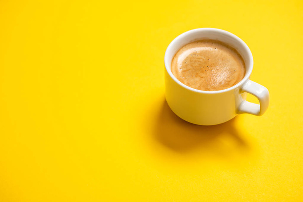 Black coffee in a cup on a yellow background - Photo, Image