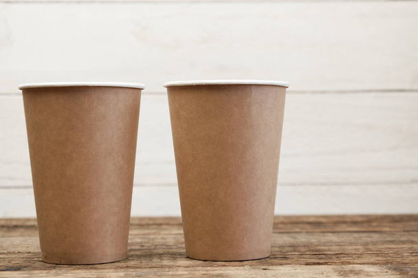 Paper cups stand on a wooden table. Wood texture - 写真・画像
