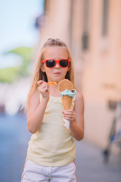 Schattig klein meisje dat 's zomers buiten ijs eet. - Foto, afbeelding