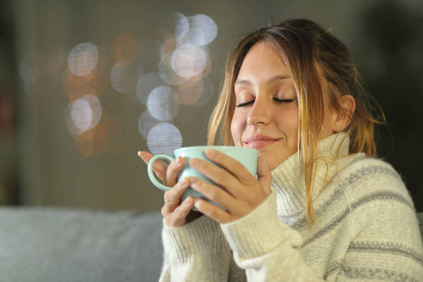 Relaxed woman in winter drinking coffee in the night - Fotoğraf, Görsel