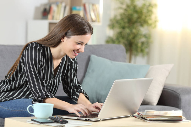 Happy woman writing on laptop sitting at home - Photo, image
