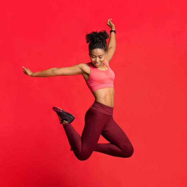 Счастливая атлетичная девушка в спортивной форме прыгает вверх
 - Фото, изображение