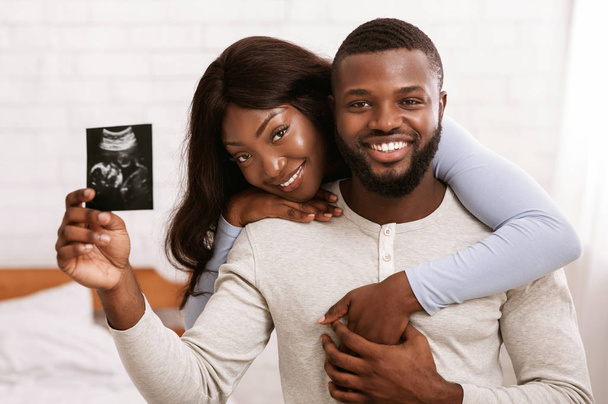 Mutlu evli çift, ellerinde bebeklerinin ultrason görüntüsü var. - Fotoğraf, Görsel