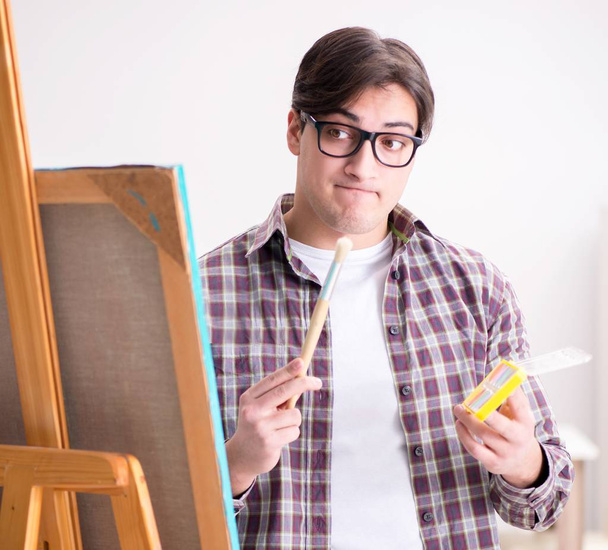 Jeune artiste masculin dessinant des images dans un studio lumineux - Photo, image