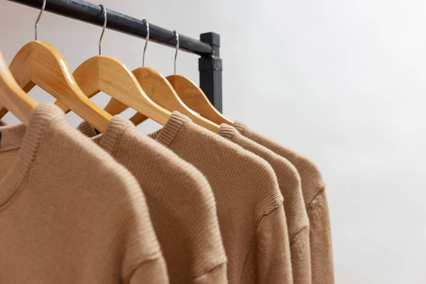 warme Wollpullover beige Farbe hängen an Kleiderbügeln - Foto, Bild