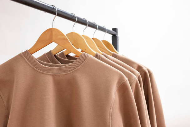 leere Sweatshirts, die an einem Kleiderbügel im Kleiderschrank oder Showroom hängen - Foto, Bild