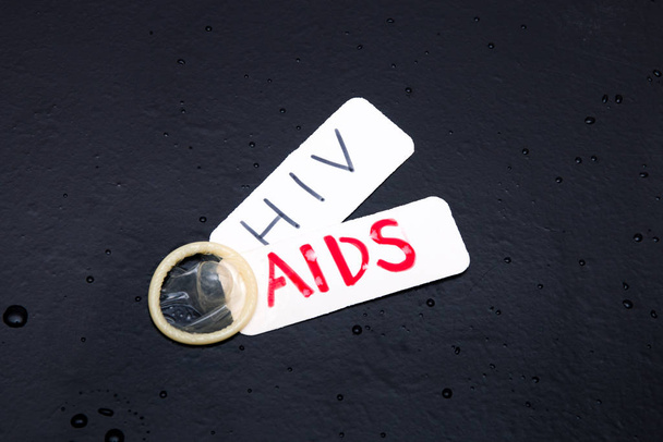 vitesse d'inscription et hiv dans un préservatif sur un espace de copie de fond noir, concept de sexe sûr
 - Photo, image