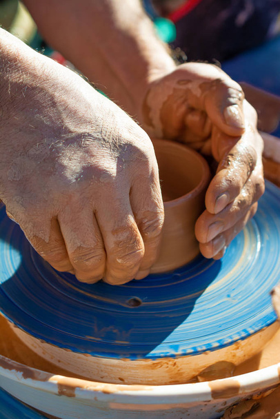 Χέρια ενός αγγειοπλάστη, δημιουργώντας ένα πήλινο βάζο στον κύκλο - Φωτογραφία, εικόνα