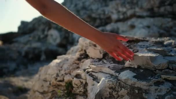 Dívka kráčí po pobřeží a dotýká se skal - Záběry, video