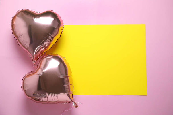 Heart shaped balloons and yellow card on pink background, flat lay. Space for text - Φωτογραφία, εικόνα