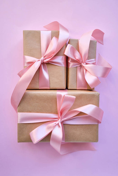 Beautiful present on pink background. Gift kraft package with ribbon and pink bow. Surprise for Christmas, Valentines Day or Mothers Day. Happy holiday mockup. Celebration event. Gift box close-up - Fotoğraf, Görsel