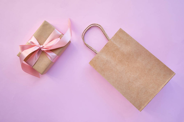 Beautiful present on pink background. Gift kraft package with ribbon and pink bow. Surprise for Christmas, Valentines Day or Mothers Day. Happy holiday mockup. Celebration event. Gift box close-up - Фото, изображение