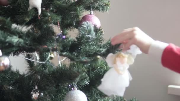 Ένα παιδί στολίζει το χριστουγεννιάτικο δέντρο με ένα παιχνίδι. - Πλάνα, βίντεο