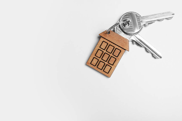 Schlüssel mit Schmuckstück in Form eines Hauses isoliert auf weiß, Ansicht von oben. Dienstleistungen für Immobilienmakler - Foto, Bild