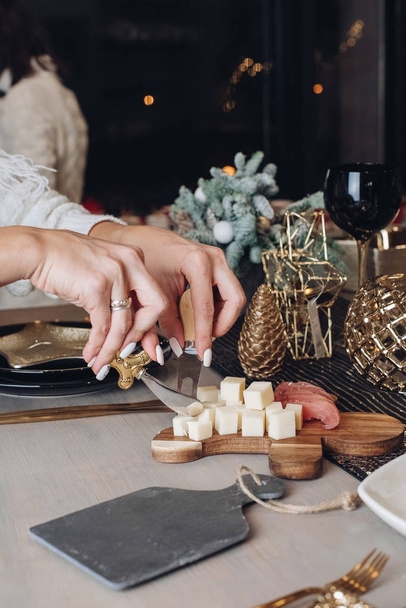 Female hands slicing a piece of cheese at the festive table - Photo, Image