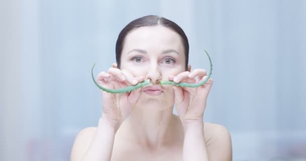 junge Frau macht lustige Gesichter mit Aloe Vera Spaß ein Konzept der organischen Körperpflege und Kosmetik auf rotem Epos gedreht - Filmmaterial, Video