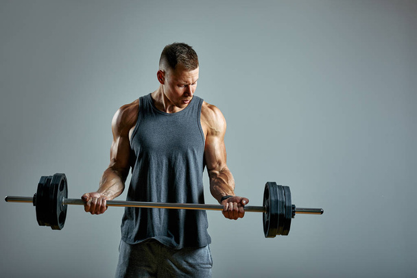 Man doing back workout, barbell row in studio over gray background. Copy space - Foto, Imagen