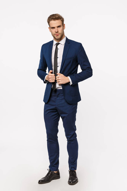 Business, company and office concept. Handsome, cheeky bearded blond businessman in classic suit, tie, put on jacket, fasten buttons looking confident and sassy, getting ready dinner, meeting - Photo, Image