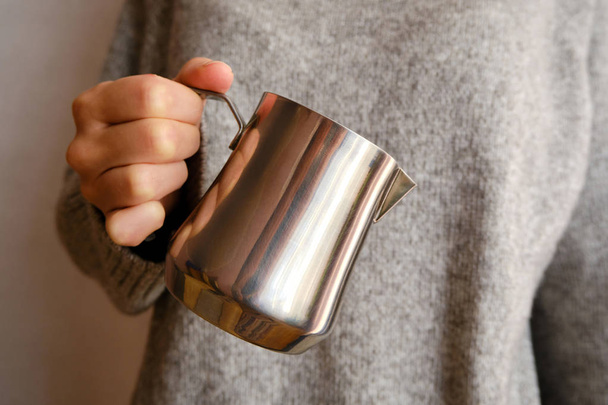 Woman hold metal milk pitcher in her hands. Barista milk pitcher closeup. Metal milk jug. Milk frother. Drinks in a cafe. Hot beverage. Equipment for making coffee. Coffee house. Professional service - Valokuva, kuva
