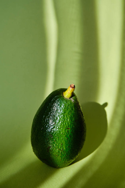 Green avocado in the sunlight in beautiful green background. Avocado closeup. Natural fresh organic eco product. Healthy eating, raw food diet. Vegetarian lifestyle. Proper nutrition. Ready to eat - Fotó, kép