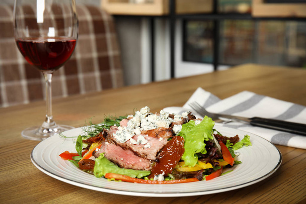 Délicieuse salade avec viande rôtie et légumes servis sur une table en bois à l'intérieur. Espace pour le texte
 - Photo, image