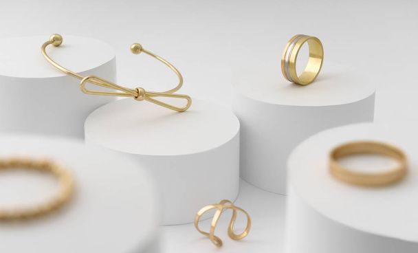 Moderna pulsera en forma de arco dorado y la colección de anillos en la plataforma de cilindros blancos
 - Foto, imagen