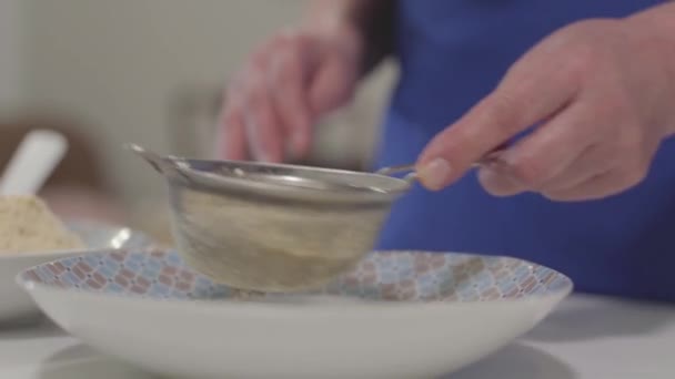 Close-up of mature female Caucasian hands sifting flour. Senior female retiree baking at home. Hobby, leisure activity. - Video, Çekim