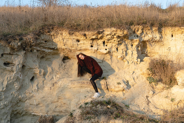Őszi fotó egy fiatal lány piros pulóverben áll a napon között a homok karrier - Fotó, kép