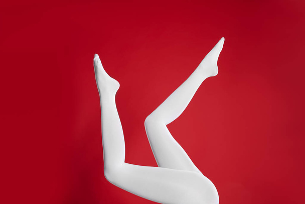 Woman wearing white tights on red background, closeup of legs - Fotoğraf, Görsel