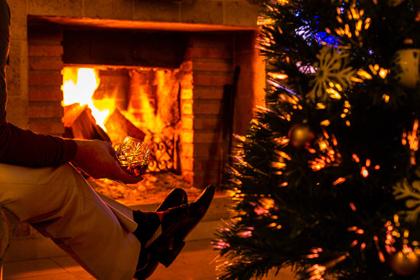 am Silvesterabend am brennenden Kamin. Weihnachten. Vorfreude auf das Fest in der Wärme und umgeben von weihnachtlichen Attributen. - Foto, Bild