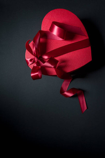 Červená dárková krabička srdce tvar s červenou stuhou na černém pozadí, dárek koncept - Fotografie, Obrázek