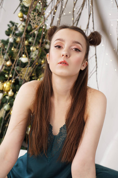 Beautiful girl in lingerie sitting on bed decorated with Christmas tree - Photo, image