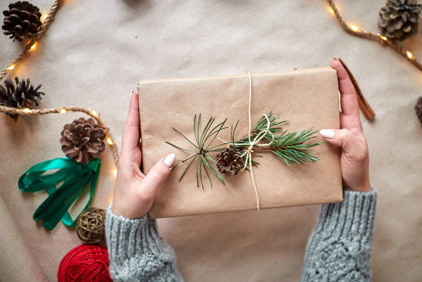 Noel hediyesini paketleyen kadın. El yapımı doğal hediye kağıdı. - Fotoğraf, Görsel