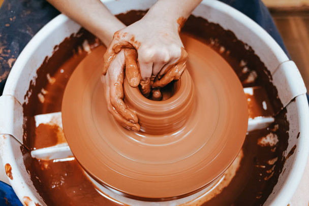 Potter tworzy gliniany dzban. Proces wytwarzania wyrobów ceramicznych. Kobieta pracuje na kole ceramicznym - Zdjęcie, obraz