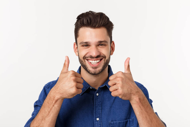 Щасливий випадковий молодий чоловік показує великий палець вгору і посміхається ізольовано на білому тлі
. - Фото, зображення