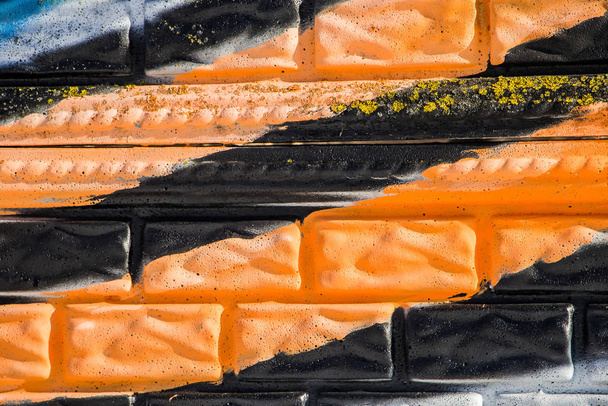 Laranja e listras pretas em uma parede de tijolo, conceito de fita de São Jorge
 - Foto, Imagem