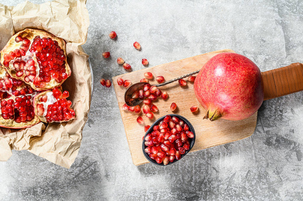 Ripe pomegranate and seeds on a wooden cutting Board. Organic fruit. Gray background. Top view - Photo, Image